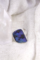 Square Opal adjustable ring shown beside a quartz crystal, with waved bezel setting and polished sterling silver band.