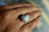 Oval Larimar adjustable ring in high-shine 925 sterling silver shown worn on the hand with ocean-blue stone.