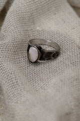 Side view of handmade Lightning Ridge Opal ring showing the raised bezel setting, textured silver band, and pale Opal face.