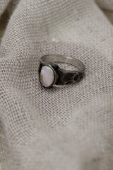 Side view of handmade Lightning Ridge Opal ring showing the raised bezel setting, textured silver band, and pale Opal face.