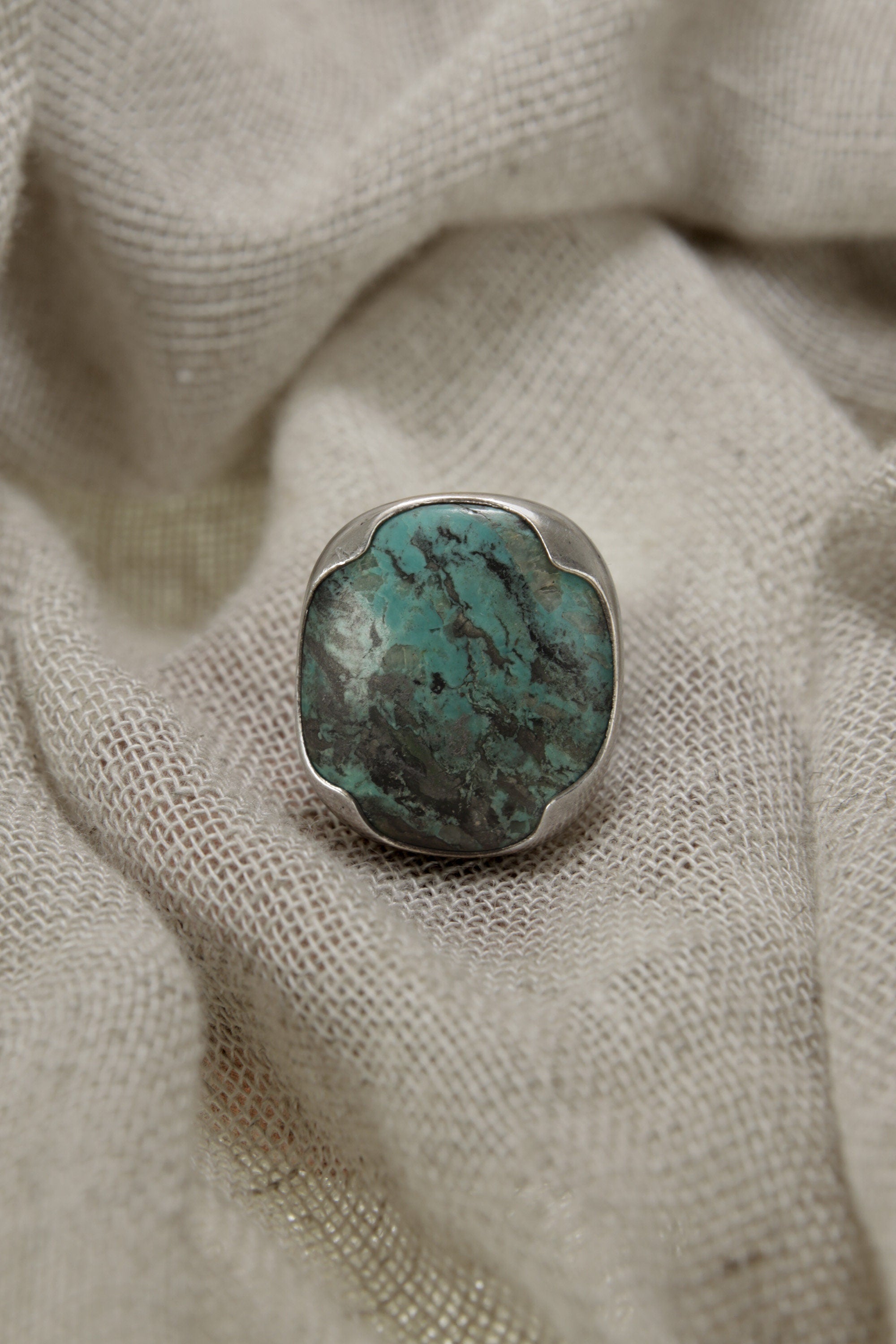 Australian Turquoise adjustable ring in high-shine 925 sterling silver shown on soft fabric with blue-green matrix stone.