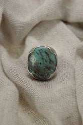 Australian Turquoise adjustable ring in high-shine 925 sterling silver shown on soft fabric with blue-green matrix stone.
