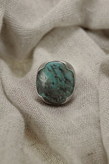 Australian Turquoise adjustable ring in high-shine 925 sterling silver shown on soft fabric with blue-green matrix stone.