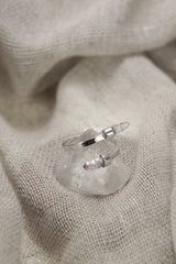 Amethyst Embrace Ring shown on soft fabric with adjustable sterling silver band and two pale purple Amethyst stones.