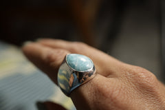 Larimar hollow sterling silver ring shown worn on the hand, with sky-blue cabochon and bold lightweight statement band.