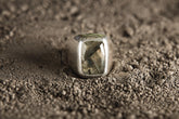 Faceted Labradorite sterling silver ring shown worn on the hand, with bold hollow band and shifting blue-green gemstone flash.