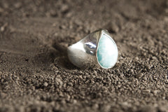 Side view of polished Larimar ring showing the raised blue cabochon, hollow silver band, and handmade statement setting.