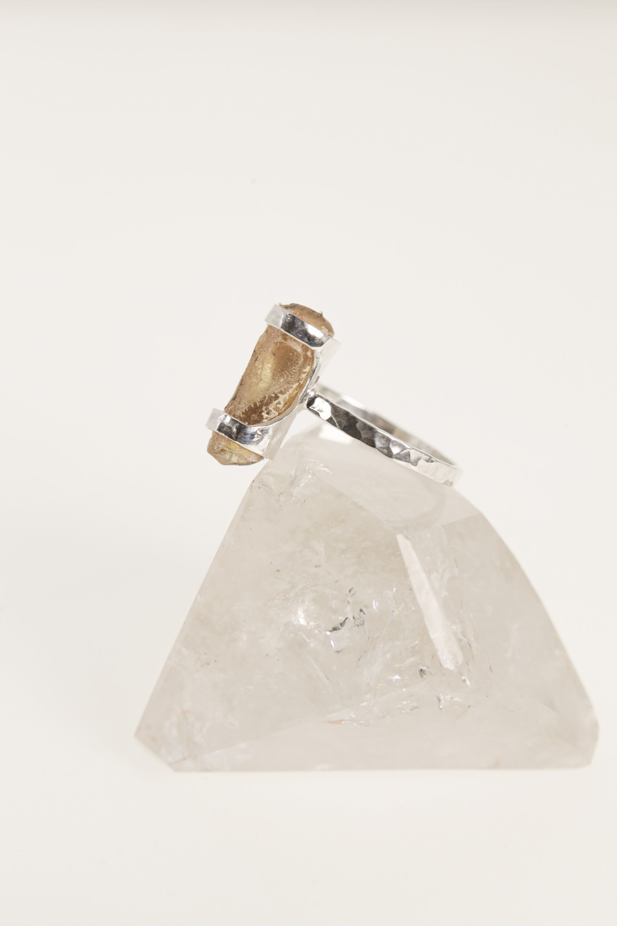 Side view of handmade Amber fossil ring on clear quartz, with polished sterling silver setting and warm organic stone.