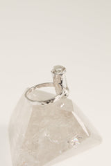 Raw Australian Aquamarine ring displayed on clear quartz, with hammered sterling silver band and pale blue-green crystal.