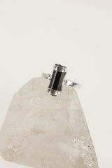 Terminated Black Tourmaline Ring shown on white crystal display from the back with open silver band and black stone.