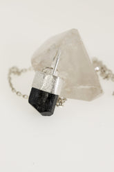 Black Tourmaline Herkimer Diamond pendant shown on black cord, with sand-textured sterling silver and arched halo bail.