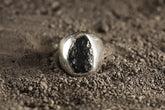 Mount Darwin Tektite Hollow Silver Ring shown on textured earth with polished sterling silver and dark impact glass stone.