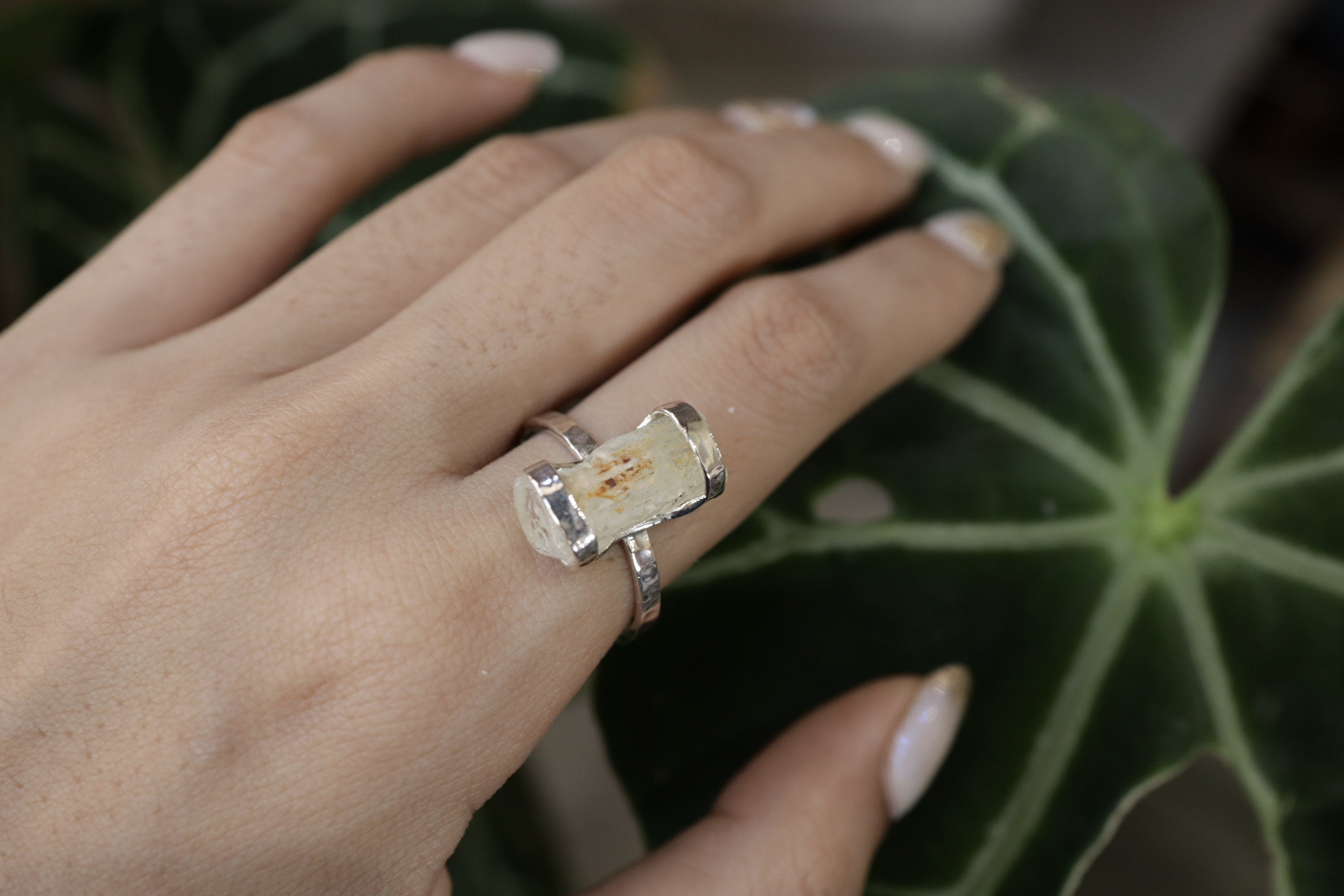 Handmade oxidized 925 sterling silver raw Australian Aquamarine ring shown worn on the hand, with pale blue crystal and hammered band.