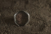 Pyrite adjustable ring in high-shine 925 sterling silver shown on earthy texture with metallic golden mineral surface.