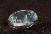 Oval Labradorite adjustable ring in high-shine 925 sterling silver shown close-up with blue-green and gold flash.