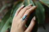 Aqua Aura Quartz Point ring shown worn on a hand, with oxidized sterling silver and luminous blue crystal setting.
