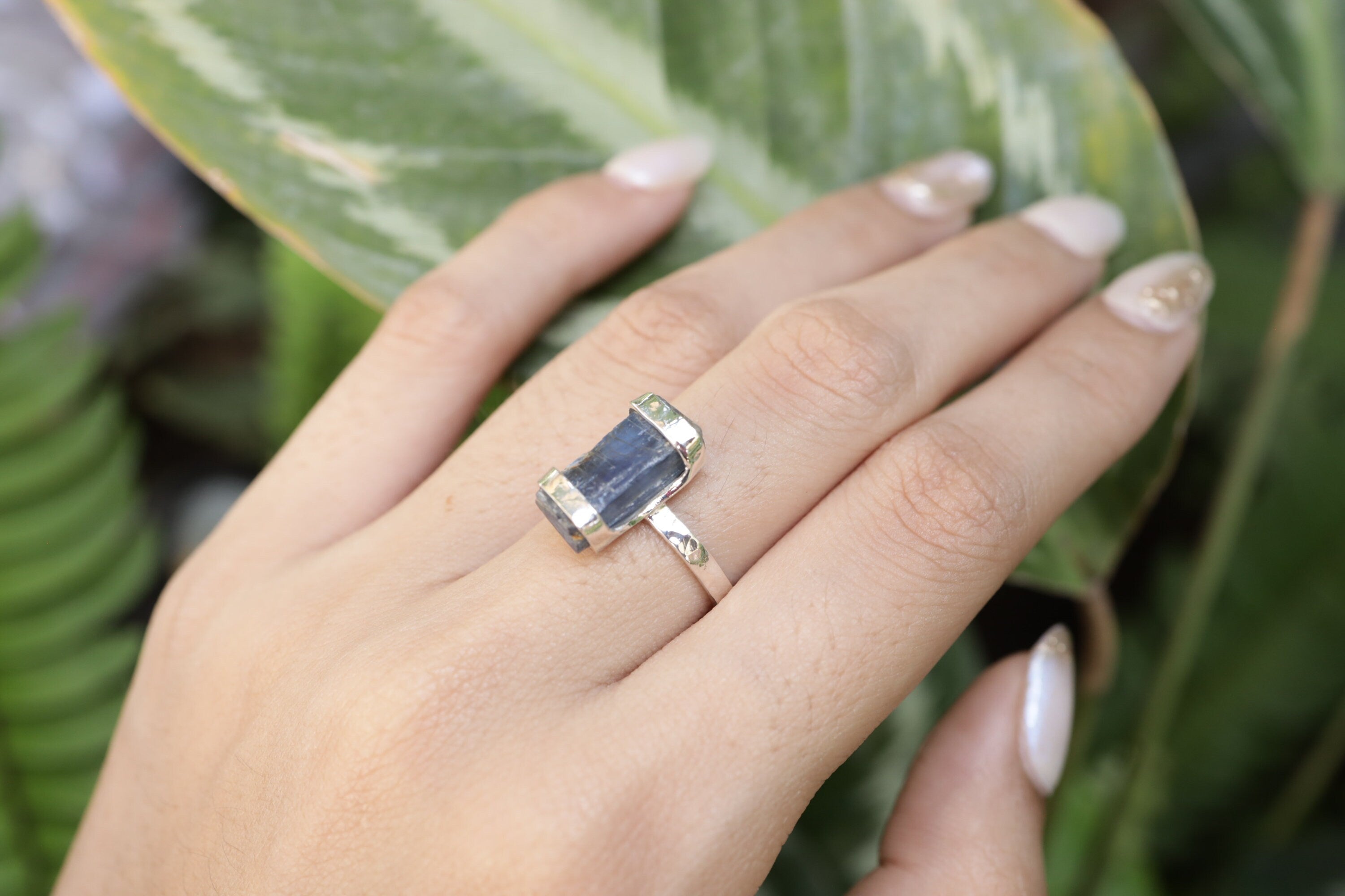 Handmade oxidized 925 sterling silver Australian Ocean Kyanite ring shown worn on the hand, with raw blue crystal and hammered band.