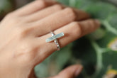 Long square cut Aquamarine silver ring shown worn on a hand, with polished hammered sterling silver and blue gemstone.
