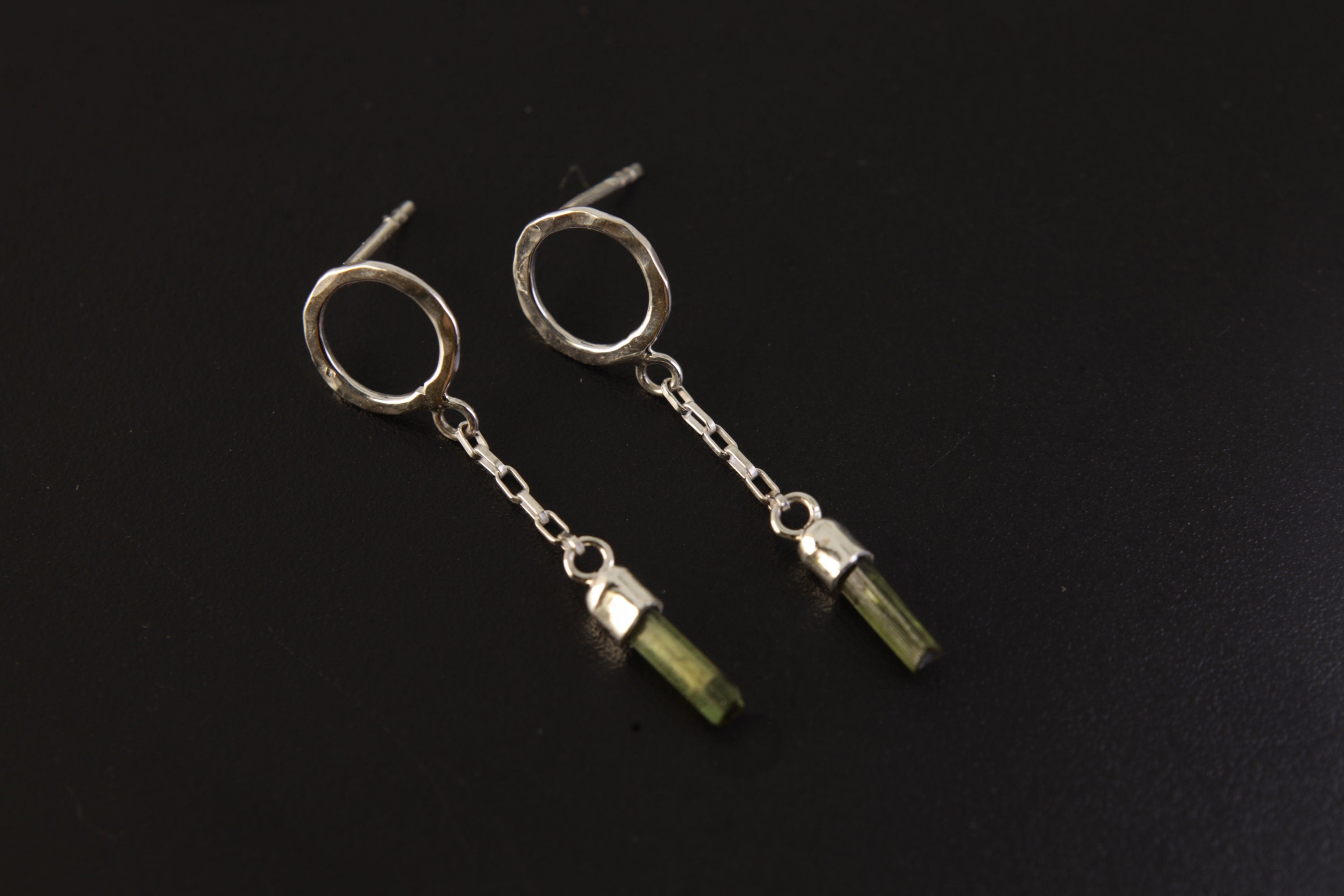 Handmade 925 sterling silver Green Tourmaline chain earrings shown on a dark background, with hammered round studs and raw crystal drops.