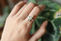 Long square cut Aquamarine silver ring shown worn on a hand, with polished hammered sterling silver and blue gemstone.