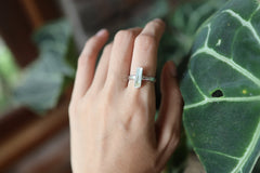 Green Tourmaline ring shown worn against tropical leaves, with polished silver and deep green crystal detail.