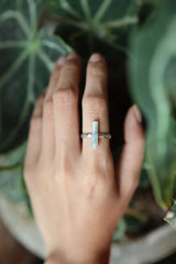 Long square cut Aquamarine ring shown worn on a hand, with polished hammered silver and calm ocean-blue gemstone.