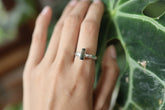 Watermelon Tourmaline sterling silver ring worn on hand against green leaves, showing hammered silver band and pink-green gemstone.