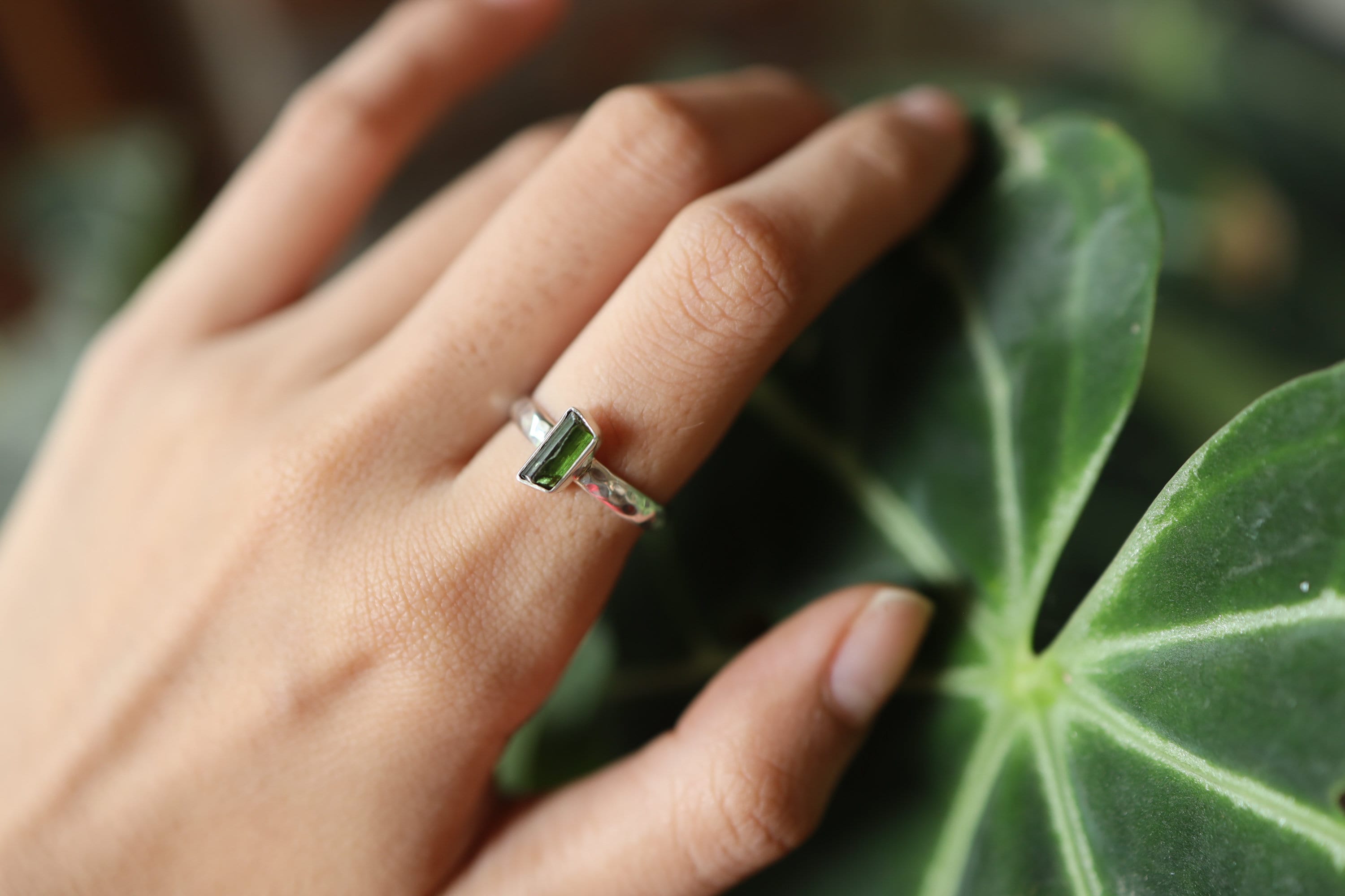 Green Tourmaline silver ring shown worn on a hand, with polished hammered sterling silver and forest-green gemstone.