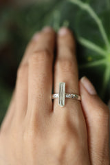 Long square cut Aquamarine ring shown worn on a hand against leaves, with ocean-blue gemstone and polished sterling silver.