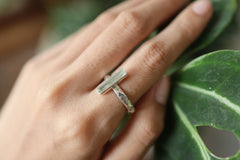 Long square cut Aquamarine silver ring shown worn on a hand, with polished hammered sterling silver and pale blue gemstone.