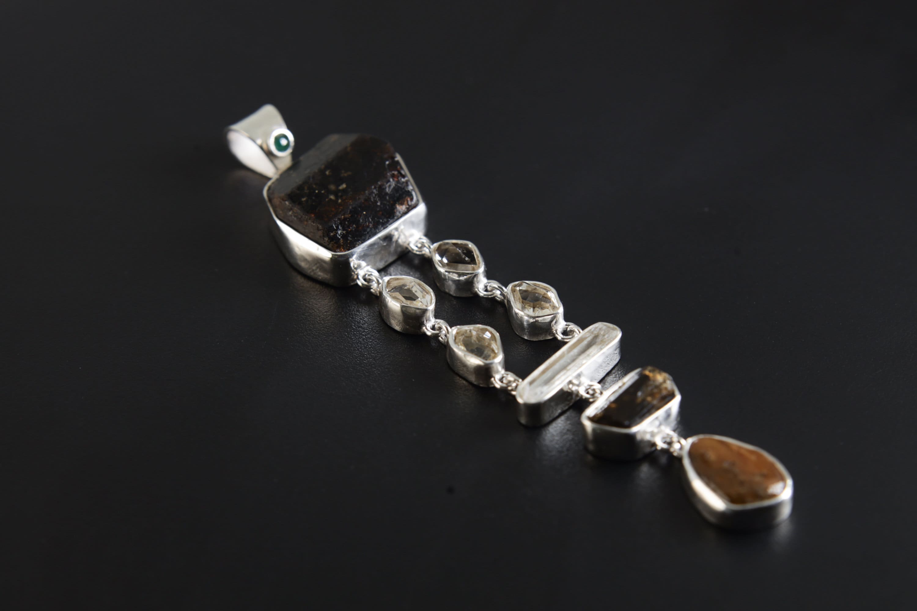 Emerald Dravite Herkimer Aquamarine Tiger Eye pendant shown on a dark background with polished sterling silver and long gemstone layout.