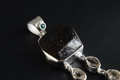 Close-up of Emerald, Dravite Tourmaline, Herkimer Diamond, Aquamarine, and Tiger Eye in a polished sterling silver pendant.