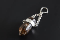 Bullet Brown Tourmaline Dravite Pendant shown on black background with high-polish sterling silver frame and chain detail.