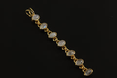 Seven-stone Rainbow Moonstone pendant displayed on dark background with long gold-plated sterling silver form.