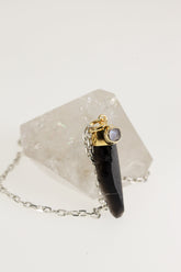 Smoky Phantom Quartz Blue Moonstone pendant displayed on Clear Quartz with gold-plated sterling silver cap and oval Moonstone.