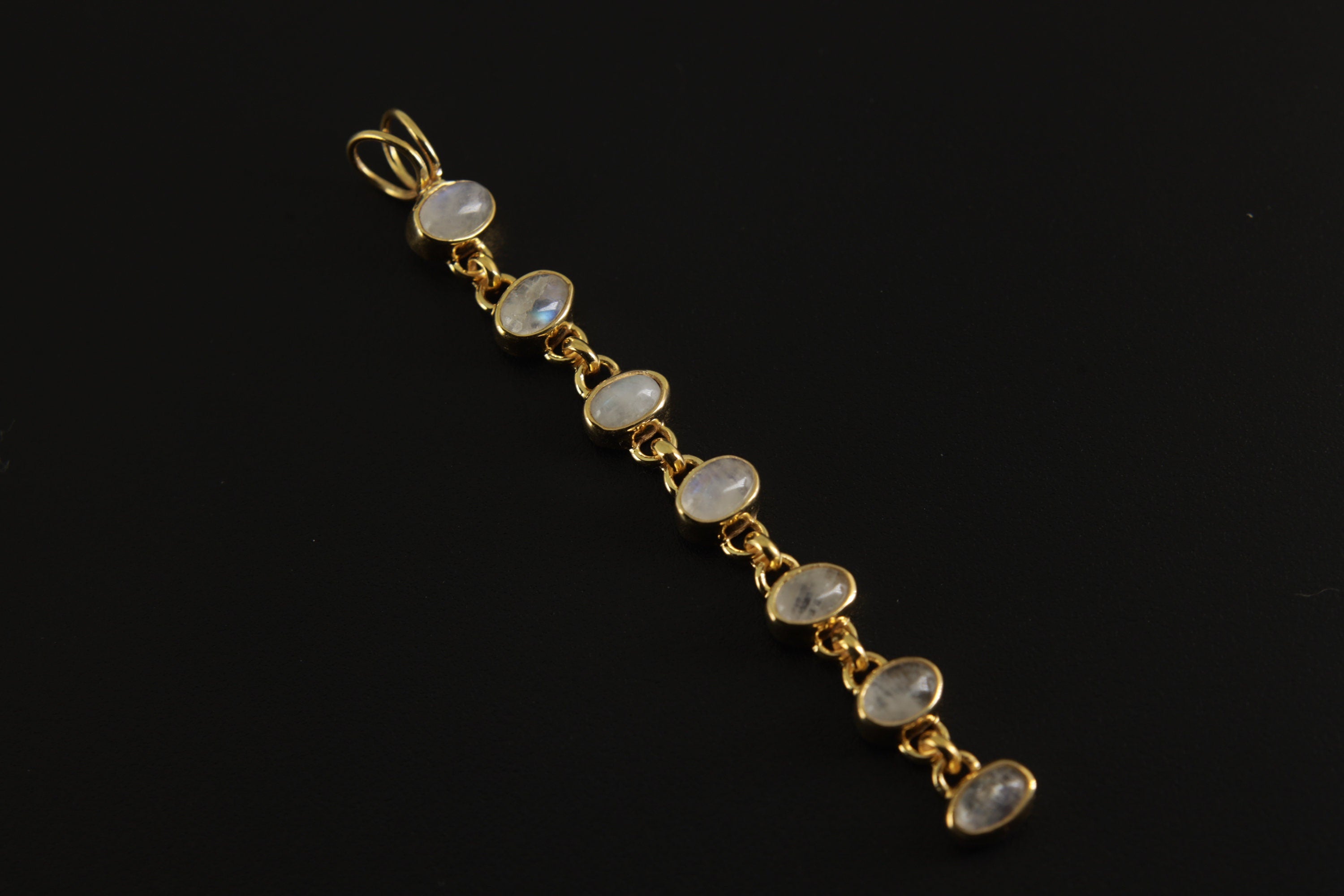 Seven Rainbow Moonstone gold-plated sterling silver pendant shown on dark background with long linked lunar design.