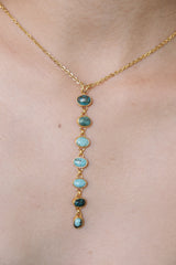 Turquoise cascade pendant shown worn on a gold-toned necklace, with seven bezel-set stones in a long vertical design.