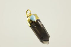 Close-up of Smoky Phantom Quartz and Larimar pendant showing teardrop blue stone set in gold-plated silver.