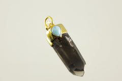 Close-up of Smoky Phantom Quartz and Larimar pendant showing teardrop blue stone set in gold-plated silver.