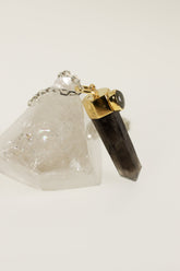 Smoky Phantom Quartz Labradorite pendant displayed on Clear Quartz with gold-plated sterling silver cap and oval flash stone.