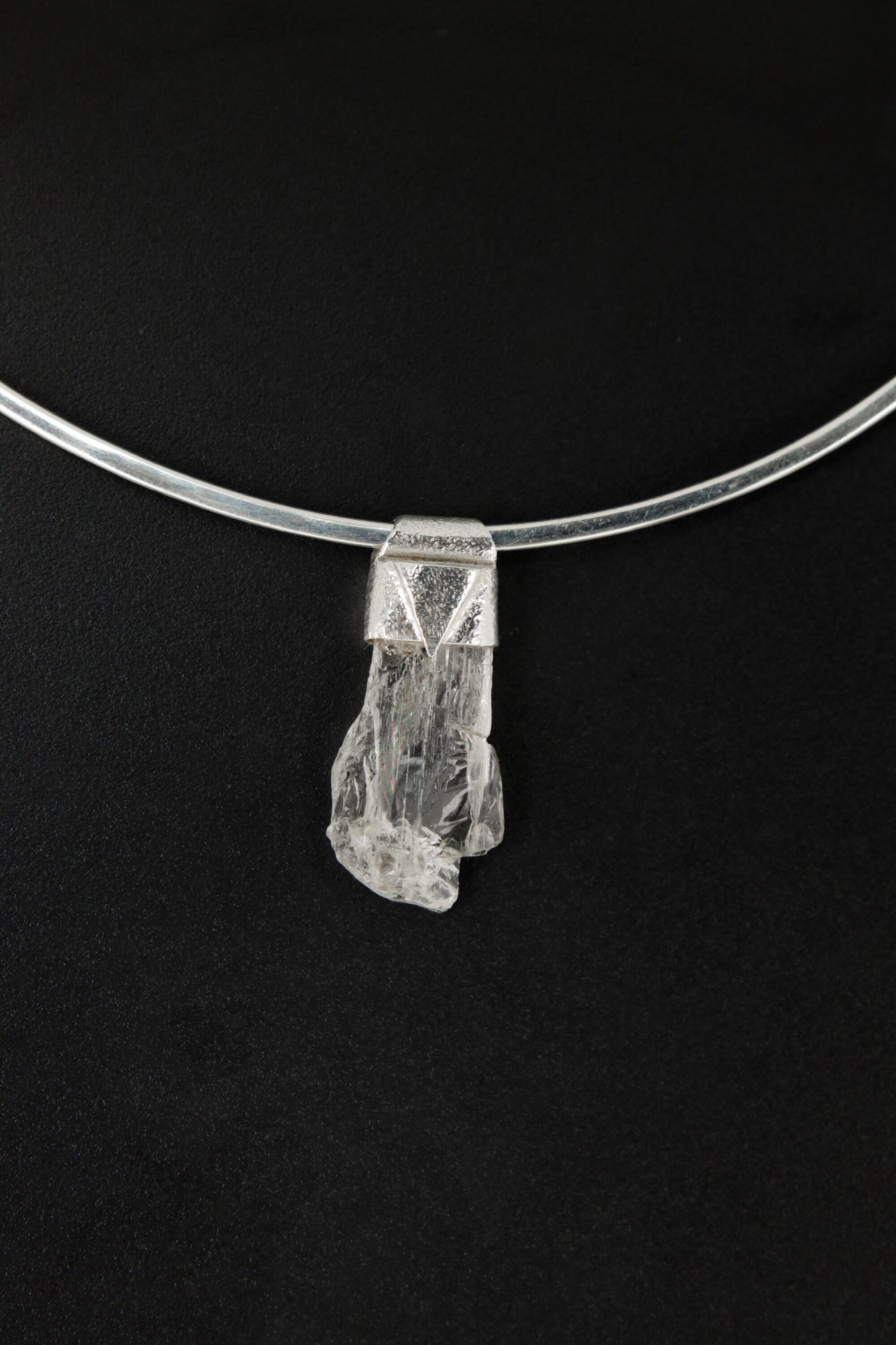 Polished Clear Himalayan Spodumene Stack Pendant shown on a black background with textured sterling silver cap.