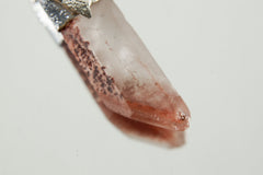 Close-up of Phantom Lithium Quartz showing lithium-bearing inclusions, warm internal colour, and natural crystal point.