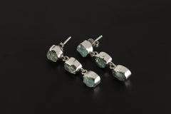 Blue Apatite geometric earrings displayed on a dark background, with three-stone sterling silver drop design.