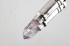 Close-up of sterling silver capsule pendant showing sand-textured surface, round bail, and opening mechanism.