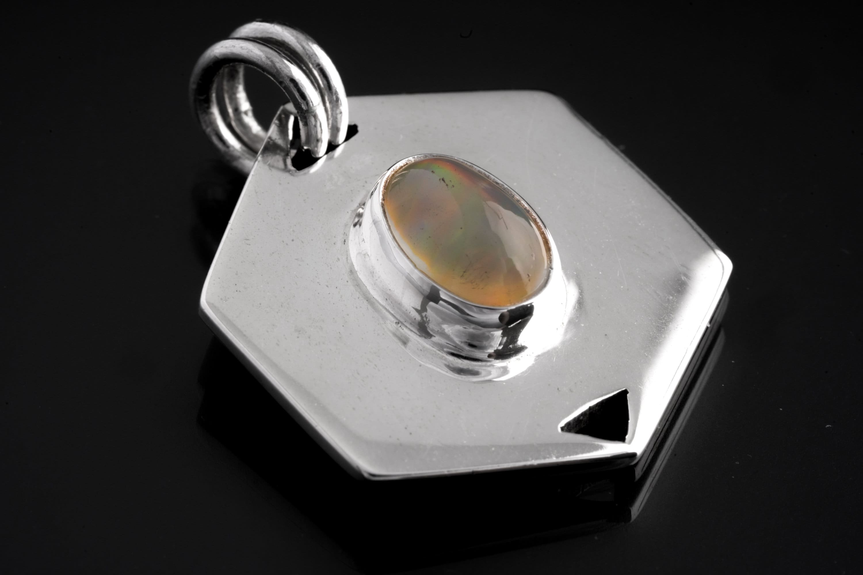 Ethiopian Opal sterling silver hexagon pendant shown on dark background with polished geometric frame.