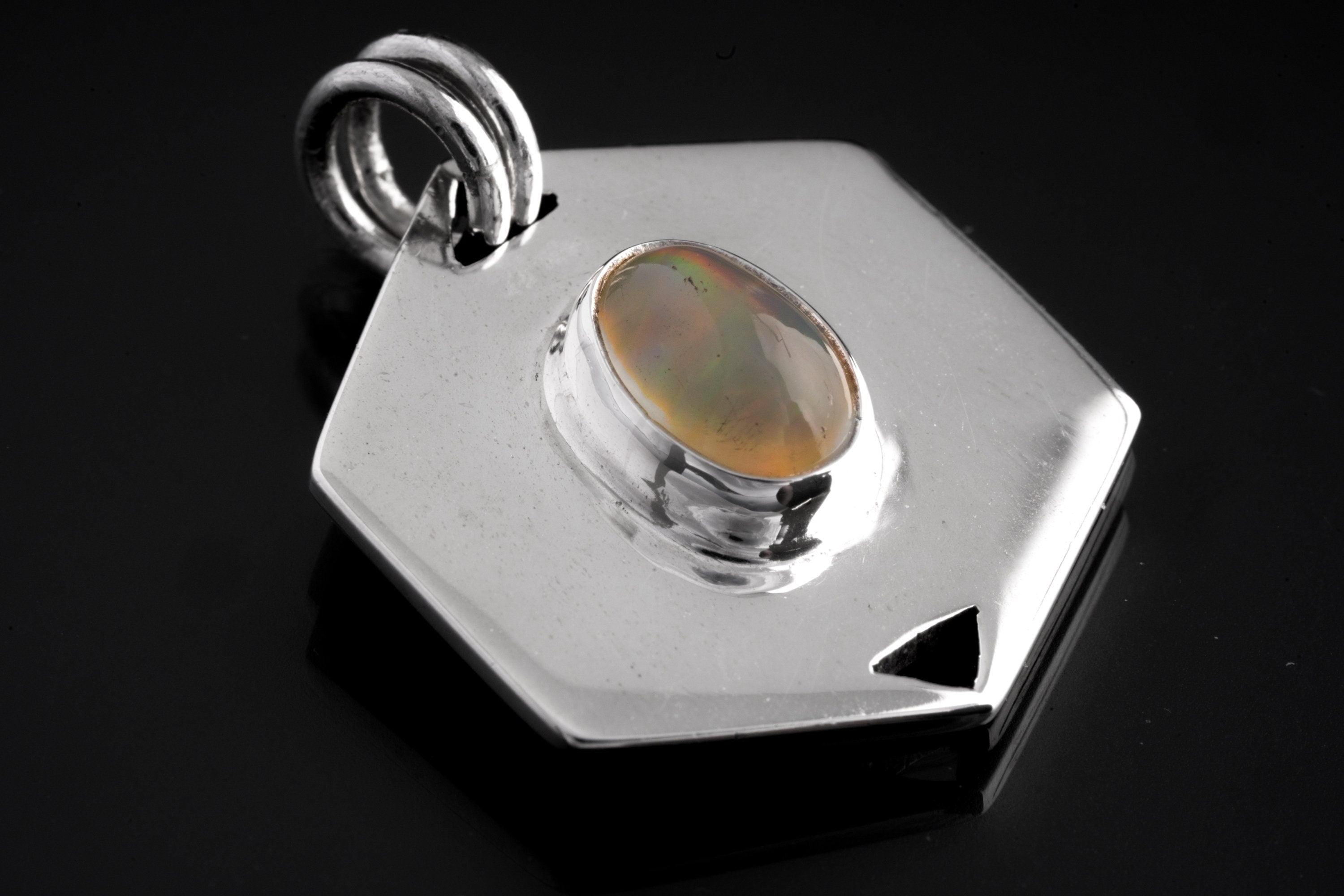 Ethiopian Opal sterling silver hexagon pendant shown on dark background with polished geometric frame.