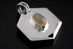Ethiopian Opal sterling silver hexagon pendant shown on dark background with polished geometric frame.