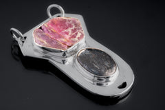 Ruby Ocean Record Keeper Pendant shown on dark background with shiny sterling silver and raw pink-red Ruby.