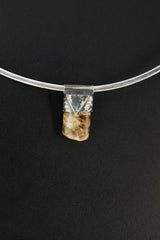 Brown Himalayan Dravite Tourmaline Stack Pendant shown on black background with silver choker and compact earthy crystal body.