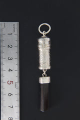 Black Tourmaline sterling silver capsule pendant shown beside a ruler for scale, with raw crystal base and round bail.